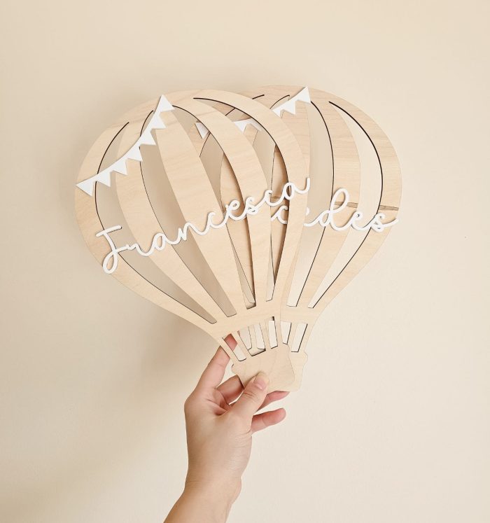 Wooden hot-air balloon wall decor held by a hand, with the name 'Francesco' in white cursive across the panels.