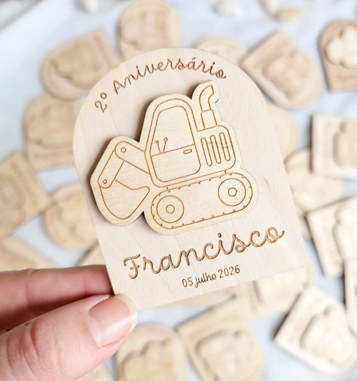 Wooden commemorative tag featuring a carved bulldozer and the text '2º Aniversário Francisco' with the date '05 julho 2026'.