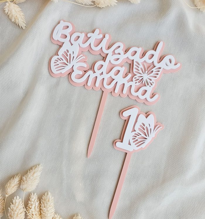 Pastel pink and white "Baby shower" sign with butterfly cutouts on a light fabric backdrop.